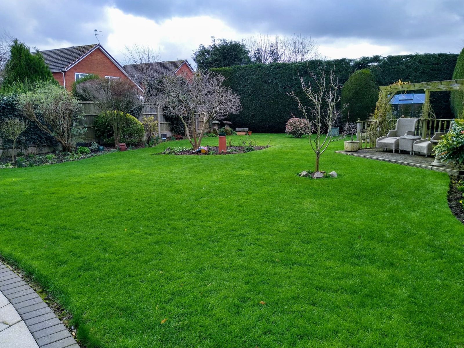 Green customer lawn with garden trees and a seating area