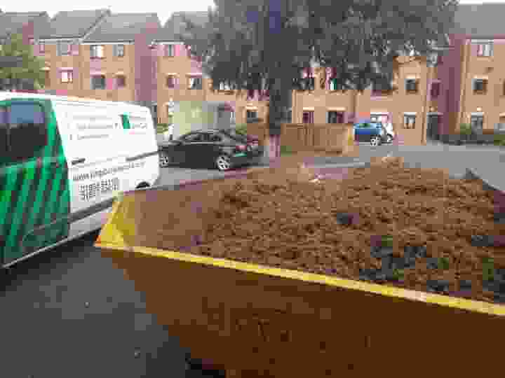 This image includes a Kingsbury Lawn Care van and a huge skip full of debris which has been produced from the lawn restoration work