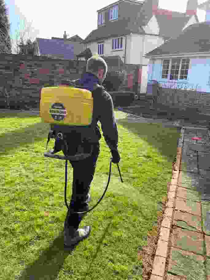 A lawn treatment being carried out via a sprayer 